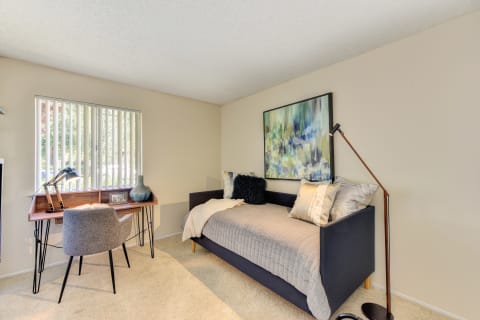Bedroom with daybed and desk. Desk is positioned in front if the bedroom window.